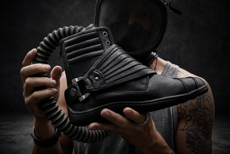 Black Wrap Boots held in front of gas mask model on dark Rebel Armada studio background