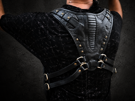 Black leather Double Rig Harness Bag worn from the back, showing the adjustable back strap system, brass-tone hardware, and sculpted leather harness panels.