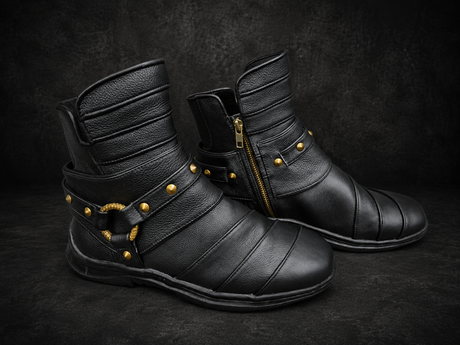 Black leather Rebel Armada ankle boots with brass hardware on dark studio background
