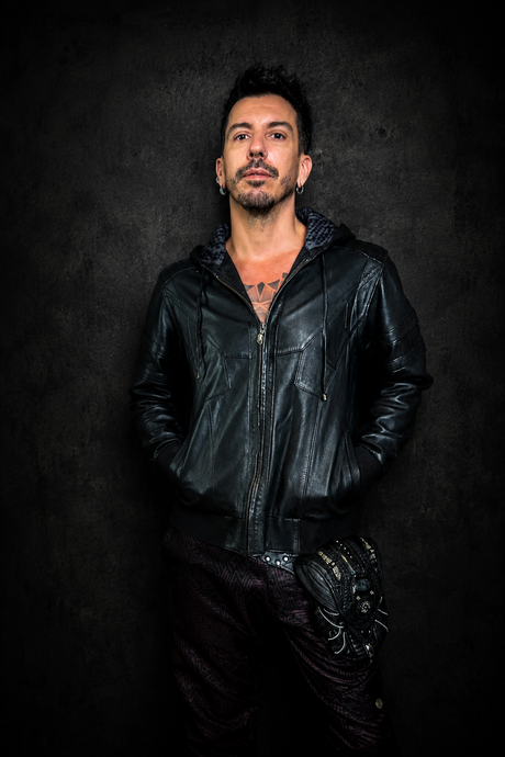 The Shadow Switch Leather Hoodie Jacket worn from the front, showing black leather body, hood, zipper closure, deep front pockets, and dark Rebel Armada studio styling.